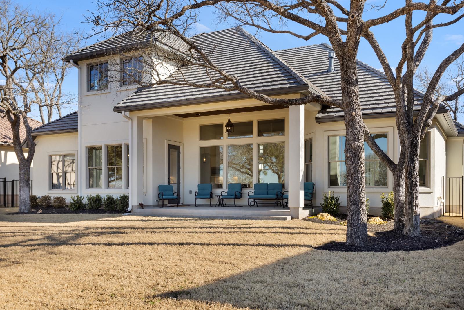 Covered back porch of a home shaded by live oaks