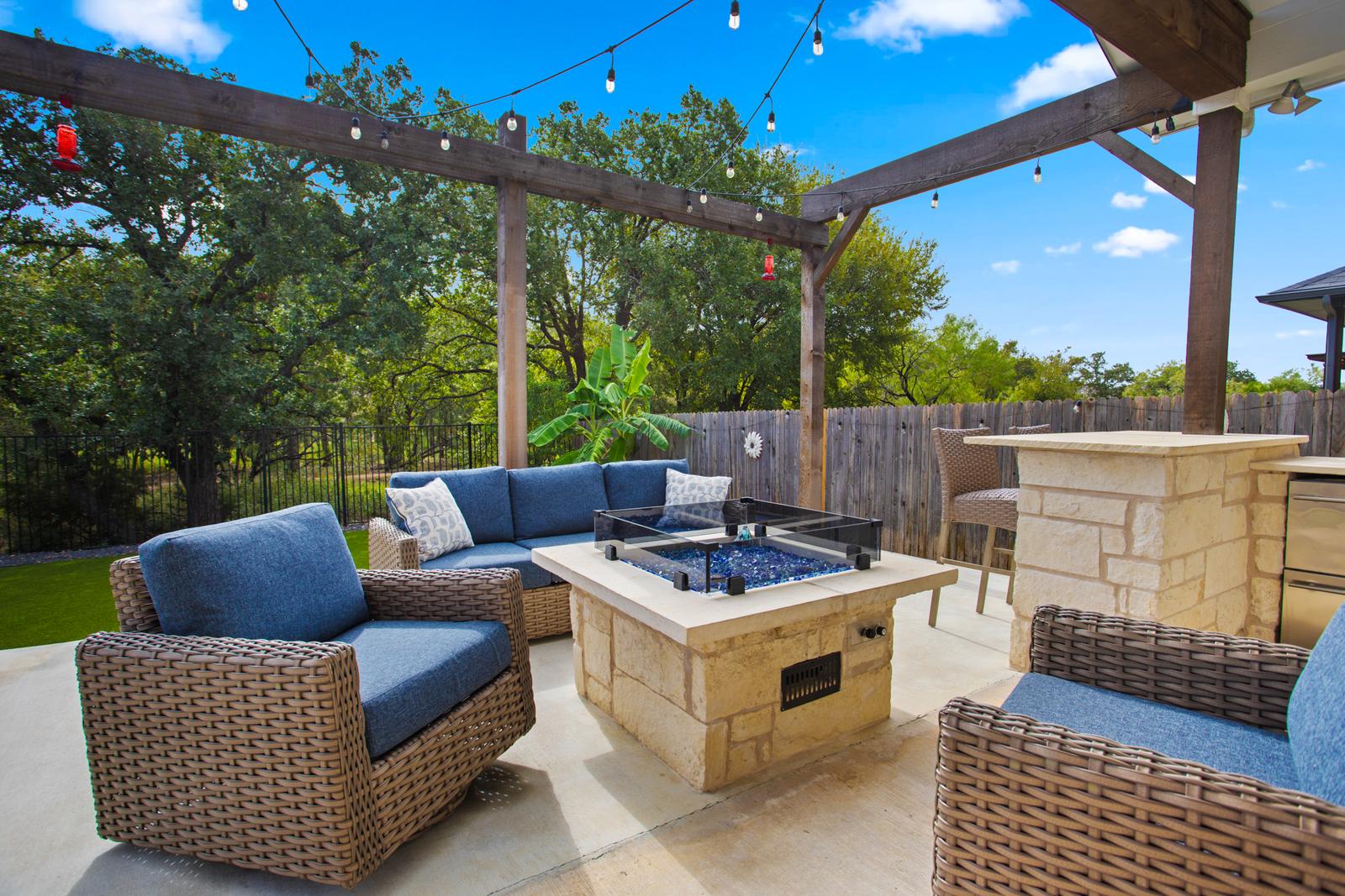 Covered backyard patio with a stone fire pit and string lights